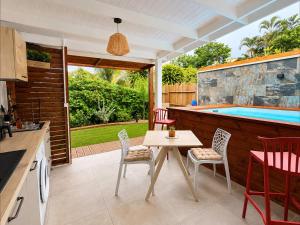 a patio with a table and chairs and a pool at Filao Cottage Bungalow avec Piscine Privée Proche plages in Sainte-Rose