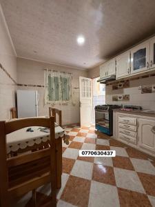 a kitchen with white cabinets and a checkered floor at حي السلام سيدالمجدوب in Sidi Mohammed Medjoub