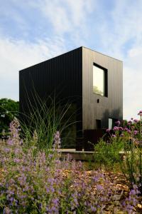 a house with a black facade and purple flowers at Oseraie Cabins - Wild lodges entre Liège et Maastricht in Visé