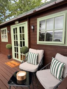 a deck with two chairs and a coffee table and a house at Swan cove - Lakeside Caravan Park in Denver