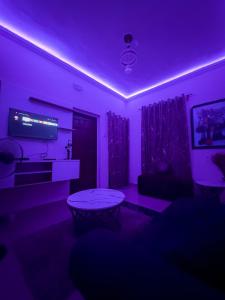 a living room with purple lighting and a table at PeaceNest in Idowu