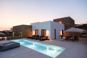a villa with a swimming pool in front of a house at Proper Stone Villa - Antiparos in Agios Georgios