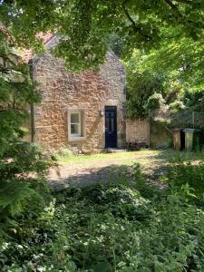 an old brick building with a black door and trees at Greenkeepers Rest in Longniddry