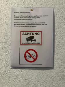 a sign hanging on a wall with a prohibiting sign at Hotel Iris- Pizzeria Ristorante La Taverna in Meersburg