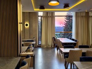 a restaurant with tables and chairs and a large window at Residence Hill Lux in Kopaonik