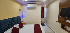 a hotel room with a bed and a tv at Hotel Sunrise View in Ahmedabad