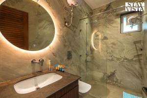 a bathroom with a sink and a shower with a mirror at StayVista at The Cloudberry Crest with BBQ & Bonfire in Rāmgarh +34 photos