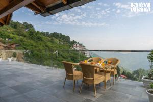 a table and chairs on a balcony with a view at StayVista at The Cloudberry Crest with BBQ & Bonfire in Rāmgarh