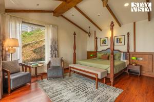 a bedroom with a bed and a chair and a window at StayVista at The Cloudberry Crest with BBQ & Bonfire in Rāmgarh