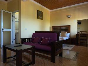 un soggiorno con un divano viola e un letto di Bel Hotel Nosy Be a Hell-Ville