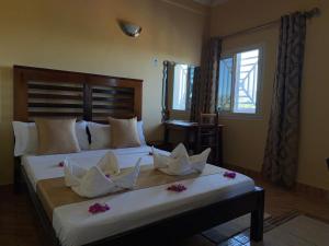 una camera da letto con un grande letto decorato con fiori di Bel Hotel Nosy Be a Hell-Ville
