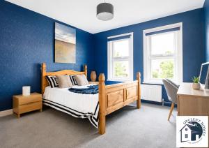 a bedroom with blue walls and a wooden bed at Contactor Stay, Reading Town Centre 4 Bed House, Large House with 2 bath in Reading