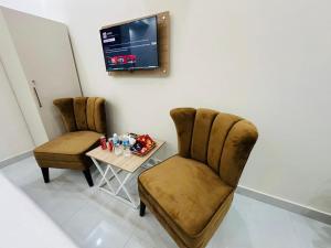 two chairs and a table in a room with a tv at Go 001 Hotel Lahore in Lahore