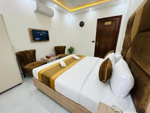 a bedroom with a large bed and two chairs at Go 001 Hotel Lahore in Lahore