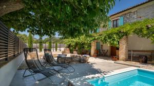 a patio with chairs and a pool in front of a house at Old House Grota by Villas Guide in Umag