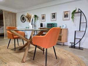 a dining room with a glass table and orange chairs at La Parenthèse du Buisson Bailly - Jacuzzi, Détente et Bien être près de Provins in Choisy-en-Brie