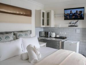 a bedroom with a white bed and a kitchen at Queens Cove in Lüderitz