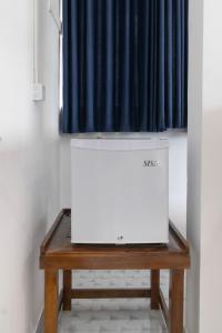 a white refrigerator sitting on top of a wooden table at Why Not Guest House, Ella in Ella +58 photos