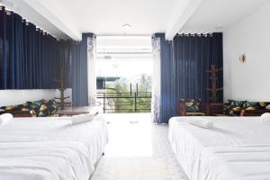 a room with three beds and a large window at Why Not Guest House, Ella in Ella