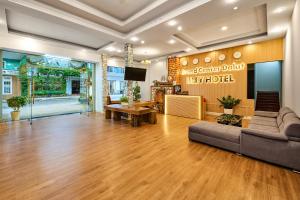 a large living room with a couch and a tv at Eluna Lilly Da Lat Hotel in Da Lat