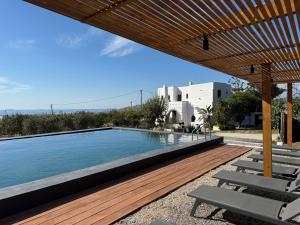 a swimming pool with a wooden deck and chairs at Villa Agrabely & Suites in Galanádhon