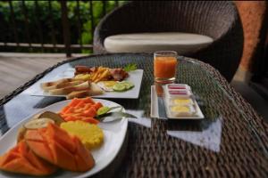 a table with two plates of food and a glass of orange juice at Hanthana Eco Lodge in Kandy