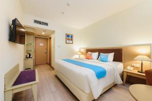 a hotel room with a large bed and a television at SANS Vibes d Grande Hotel Batam in Nagoya +23 photos