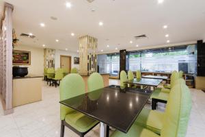 a dining room with a table and green chairs at SANS Vibes d Grande Hotel Batam in Nagoya