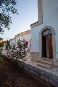 a white building with a door in a yard at Casale del Murgese Country Resort in Savelletri di Fasano