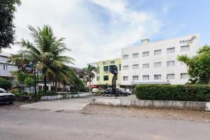 a building with a palm tree in front of a street at SANS Vibes d Grande Hotel Batam in Nagoya