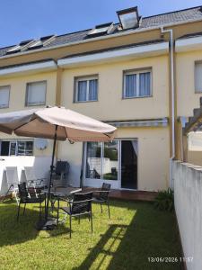 a table and chairs with an umbrella in front of a house at ADOSADO Avda BREOGAN 71 in Foz
