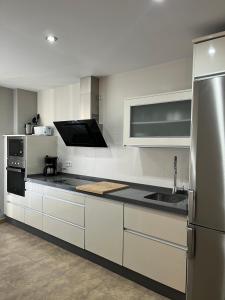 a kitchen with white cabinets and a stainless steel refrigerator at Duplex Jalama II in Moraleja
