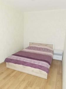 a small bed in a white room with a wooden floor at Апартамент Централ in Targovishte +5 photos