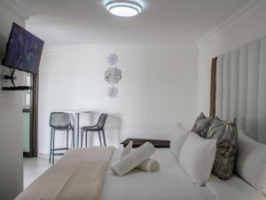 a white bedroom with a bed and a table and chairs at Queens Cove in Lüderitz