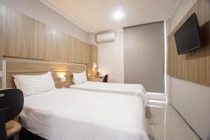 a hotel room with two beds and a flat screen tv at Townhouse Oak Hotel Damar Kurung in Gresik +16 photos