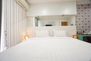 a white bed with white pillows in a room at Townhouse Oak Hotel Damar Kurung in Gresik