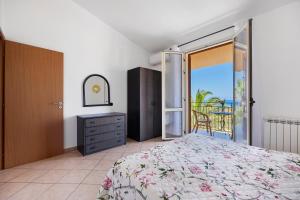 a bedroom with a bed and a balcony with the ocean at Casa Onda Azzurra in Balestrate