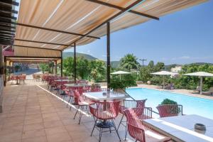 a patio with tables and chairs next to a swimming pool at Hotel Aristotelis in Ancient Epidauros
