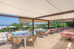 a patio with tables and chairs and a pool at Hotel Aristotelis in Ancient Epidauros