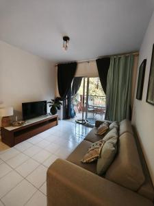 a living room with a couch and a television at Paphos-Limnaria Garden in Paphos