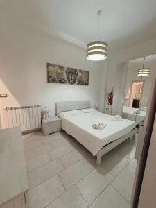 a white bedroom with a bed and a mirror at Il gingillo di Alice by Maniel Beach Hotel in Letojanni