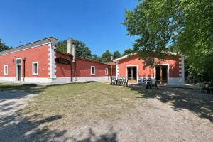 a red building with tables and chairs in front of it at Casa Natura Gargano in Monte SantʼAngelo