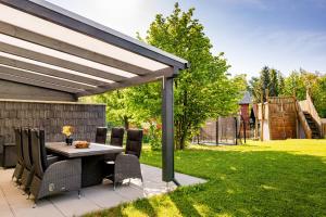 a patio with a table and chairs under a pergola at Ferienhaus Bimmelbahn 2 - Familienferienhaus 100 m am Dampflokbahnhof Sauna Trampolin Spielezimmer in Olbersdorf