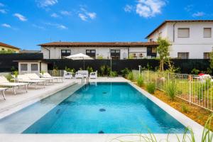 a swimming pool with tables and chairs in front of a house at Villa Fedora Luxury Suites in Lucca