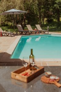 a bottle of wine and a wine glass next to a swimming pool at Moulin de Longuecoste, 11 couchages, Nature, Rivière, Piscine et Pool House in Montet-et-Bouxal