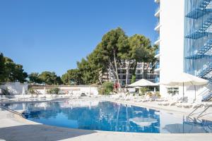 a swimming pool with chairs and umbrellas and a building at Inter 2 in Salou