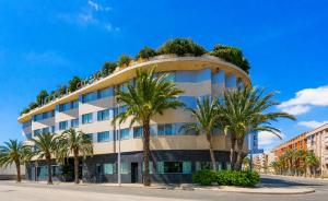 a building with palm trees in front of it at Hotel Areca in Torrellano
