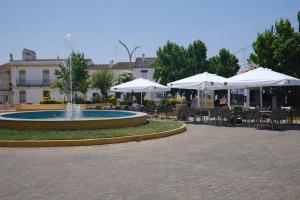 a fountain in a courtyard with tables and white umbrellas at Solar Verbena in Vaiamonte