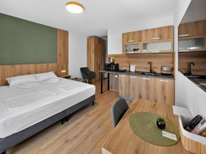 a bedroom with a bed and a table and a kitchen at ParkNest - Apartmani i sobe in Apatin