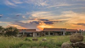 a house in a field with a sunset in the background at The Kingdom Resort in Ledig